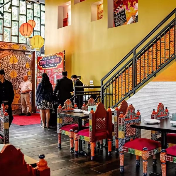 The vibrant interior of Bombay Street Food, featuring colorful Indian decor, ornate chairs, and a grand staircase.