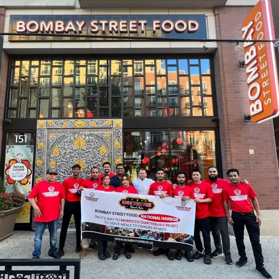 Bombay Street Food staff holding a banner for Morocco earthquake relief in front of the restaurant.