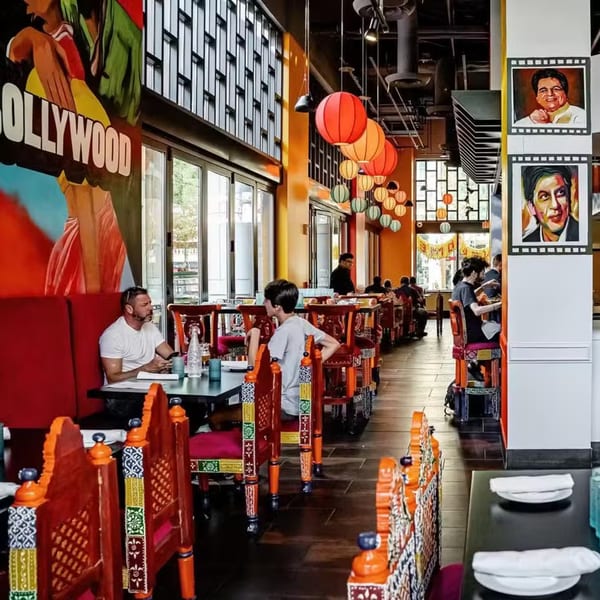 Diners seated at tables in Bombay Street Food, featuring colorful chairs, Bollywood posters, and hanging lanterns.